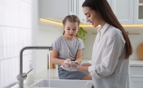 Mama și fetița se spală pe mâini la chiuveta din bucătărie