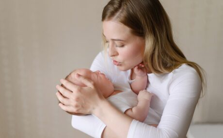 Mama își ține bebelușul în brațe și încearcă să-l calmeze din plâns